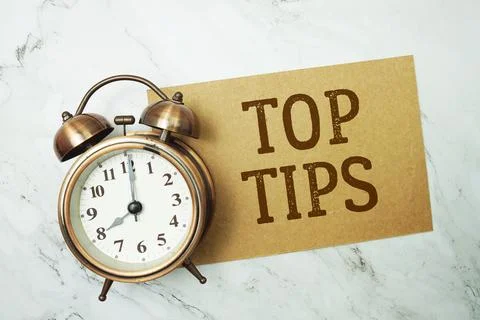 Top Tips text written on paper card with alarm clock on marble background Stock Photos