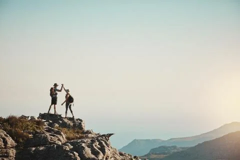 The top is top priority. a man and woman hiking up a mountain. Stock Photos