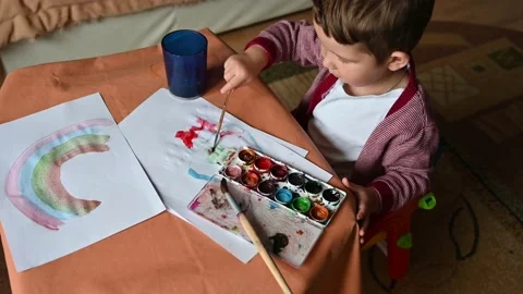 Top view of 2 years old boy draws a rainbow with paints. Stock Footage 171381601