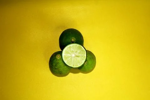 Top view of 3 and a half limes on a yellow background. Stock Photos