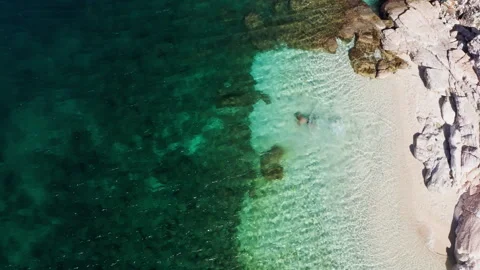 Top View 4K Drone Footage of Man Swimming by White Pebble Beach Видео 337433445