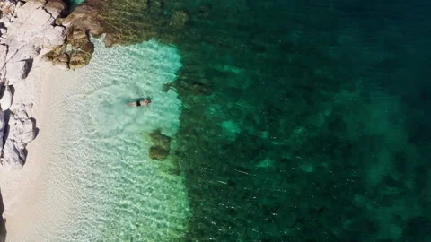 Top view 4K drone video of man swimming and relaxing on lonely white pebble beac Stock Footage 322078925