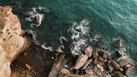 Top view 4k footage of ocean blue waves break on high cliff of a rocky mountain. Vídeo Stock 156537448