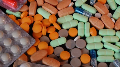 Top View 4K - Rotating Mixed Pills and Capsules on White Blister Pack - Medicine Stock Footage 331088731