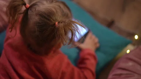 Top view absorbed Caucasian blond little girl watching online cartoons on Video stock 219915996
