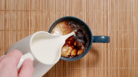 TOP VIEW: Adding cream to a cup. Milk coffee. Slow motion. Vídeos de archivo 144415932