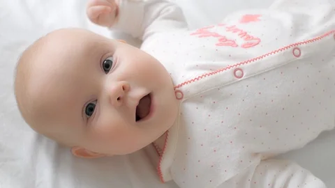Top view adorable cute smiling toddler laughing lying on bed medium close up Stock Footage 129680599