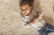 Top View Of Adorable Little African American Girl Lying On Carpet At Home Stock Photos