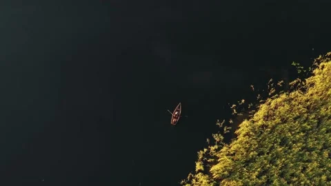 Top view aerial background shot of two people rowing small boat on idyllic still Stock Footage 152474586