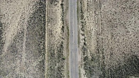 Top View Aerial of a White Car Driving Down Weathered Road Stock Footage 200867698