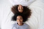 Top View African American Teen Daughter Lying On Bed With Mother Stock Photos