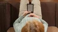 Top View: Aged Woman With An E-Book On A Sofa At Home Stock Footage