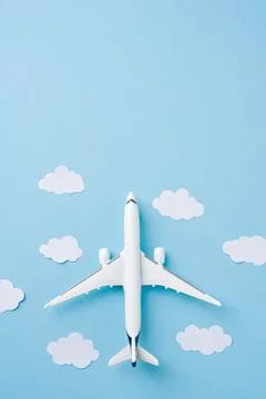 Top view airplane with paper clouds on blue background Stock Photos