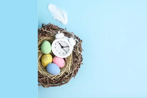 Top view of alarm clock, easter eggs and nest flatlay. Stock Photos