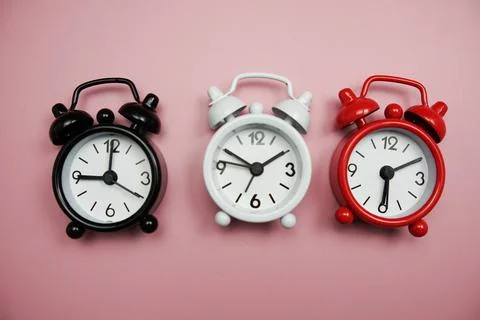 Top view of alarm clocks with different time Flat lay composition on pink  ba 库存照片