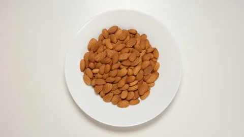 TOP VIEW: Almonds fill a white dish (stop motion) Stock Footage 69809498