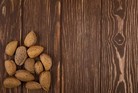 Top view of almonds in shell scattered on wooden background with copy space Stock Photos