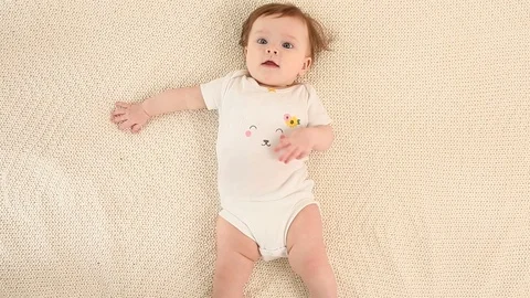 Top view and close-up portrait of cute adorable baby girl wearing white body Stock Footage 93459041