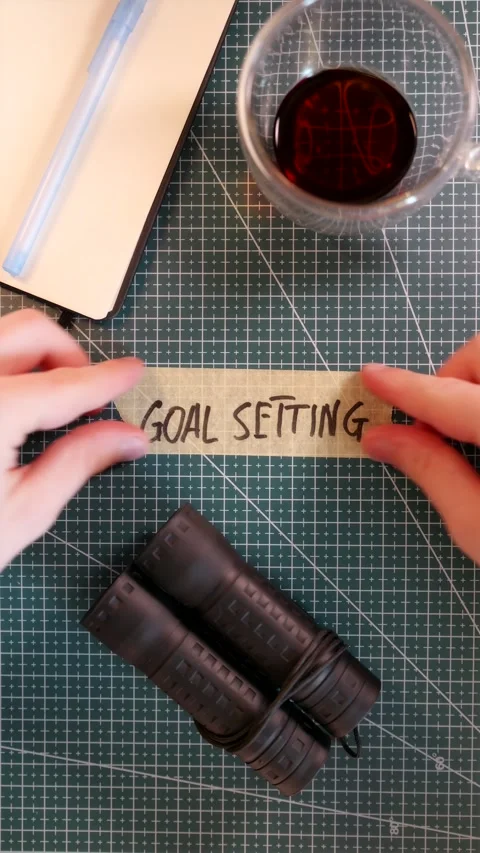 Top view of applying GOAL SETTING handwritten tape near coffee cup Stock Footage 338183568