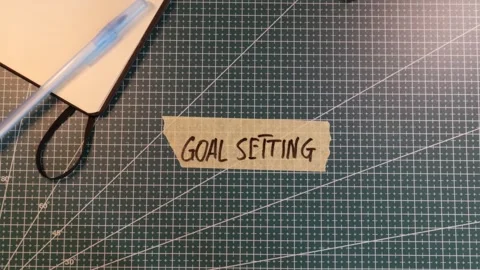 Top view of applying GOAL SETTING handwritten tape near coffee cup. Stock Footage 338183873