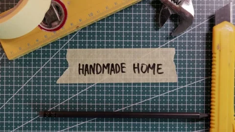 Top view of applying HANDMADE HOME tape sticker on green mat. Stock Footage 337816294