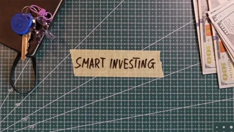 Top view of applying SMART INVESTING tape sticker near money and wallet Stock Footage 338183834