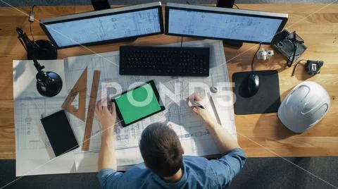 Top View of Architectural Engineer Draws on His Blueprints, Compares with Tablet Stock Photos