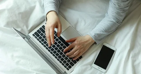 Top view of asian woman putting smart phone by lasptop computer and using it Video stock 73590553