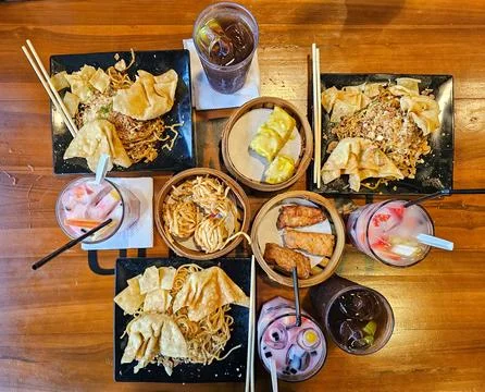 Top View of Assorted Asian Food Platters and Beverages on Wooden Table Stock Photos