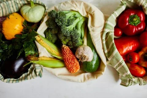 Top view assorted fresh vegetables in reusable cotton bags on table in the ki Stock Photos