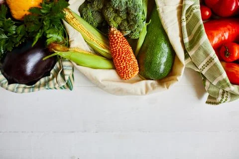 Top view assorted fresh vegetables in reusable cotton bags on table in the ki Stock Photos