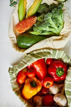 Top view assorted fresh vegetables in reusable cotton bags on table in the ki Stock Photos
