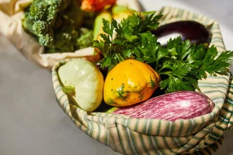 Top view assorted fresh vegetables in reusable cotton bags on table in the ki Stock Photos