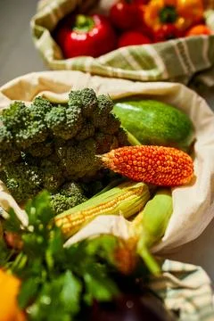 Top view assorted fresh vegetables in reusable cotton bags on table in the ki Stock Photos