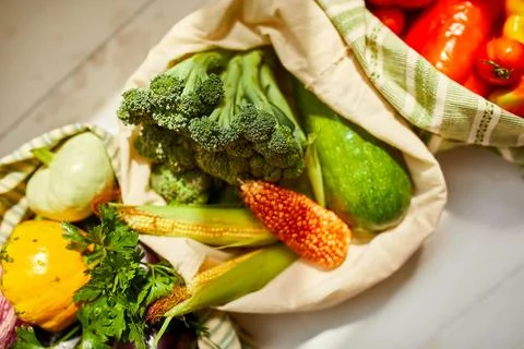 Top view assorted fresh vegetables in reusable cotton bags on table in the ki Foto stock