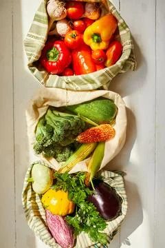 Top view assorted fresh vegetables in reusable cotton bags on table in the ki Stock Photos