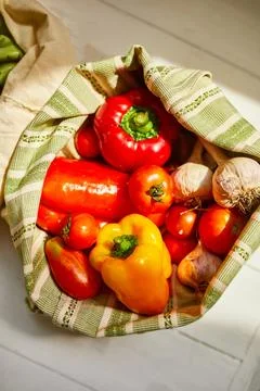 Top view assorted fresh vegetables in reusable cotton bags on table in the ki Stock Photos
