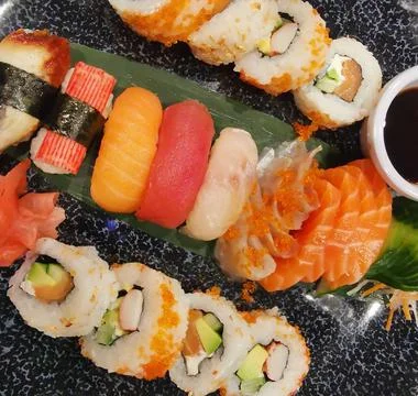 Top view of assorted sushi and soy sauce on dark platter Stock Photos
