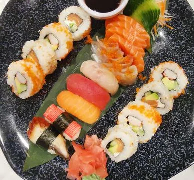 Top view of assorted sushi and soy sauce on dark platter Stock Photos