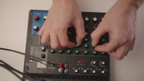 Top view of audio engineer working on compact sound mixer, manipulating various Stock Footage 323451301