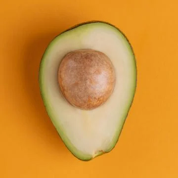 Top view on avocado half on orange background Stock Photos