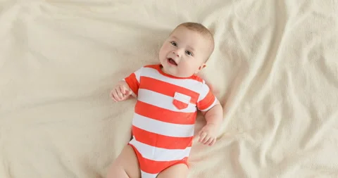 Top view of the baby looking in the camera and smiling, close up 4k shot.  Stock Footage 126494633