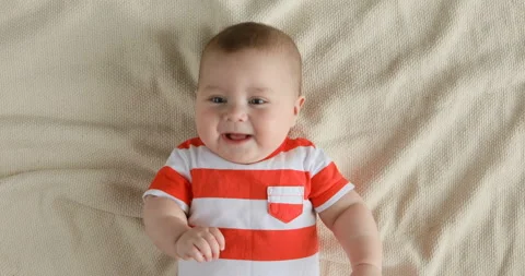 Top view of the baby looking in the camera and smiling, close up 4k shot. A cute Stock Footage 126495156
