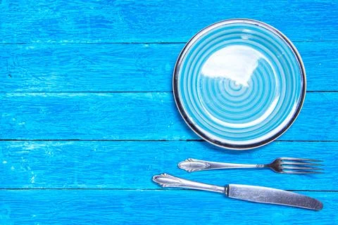 Top view background with empty blue ceramic plate, antique silver cutlery on Stock Photos