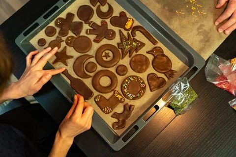 Top view of a baking sheet with gingerbread biscuits of different shapes while Stock Photos