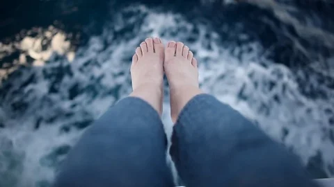 Top view at bare feet and blue sea at vacation. Feet hang from an edge of yacht. Stock Footage 73426518