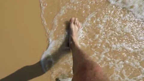 Top view of bare feet walking on a sandy beach, washed by water Stock Footage 149455020