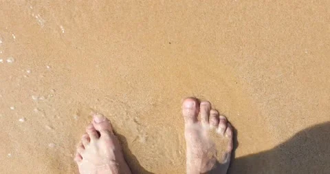 Top view of bare feet walking on a sandy beach, washed by water Stock Footage 149455076