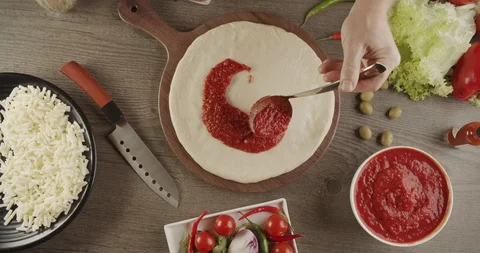 Top view of the base for pizza is added from metal ladle natural tomato sauce Stock Footage 123996783