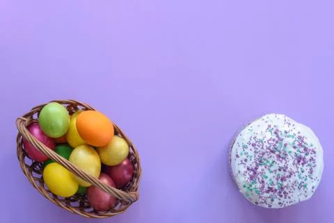 Top view on basket with easter eggs and on cake, purple background Foto stock